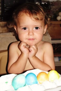 child striking a pose with his colored easter eggs